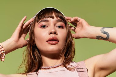 Şık bir genç kadın, poz verirken ve saçlarını ustalıkla şekillendirirken kendine güvenir..