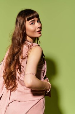 Uzun saçlı genç bir kadın çekici bir poz verirken şık elbisesini sunar..