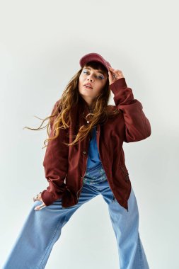 Parlak giyimli genç bir kadın minimalist bir arkaplana karşı şık bir elbise içinde poz veriyor..