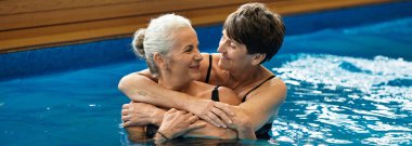 İki güzel olgun kadın, huzurlu bir sağlık merkezinde, hayatı kucaklayan neşeli bir anı paylaşıyor..