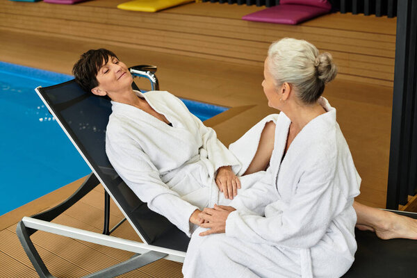 Two beautiful mature women enjoy a tranquil moment at a wellness center, embracing relaxation.