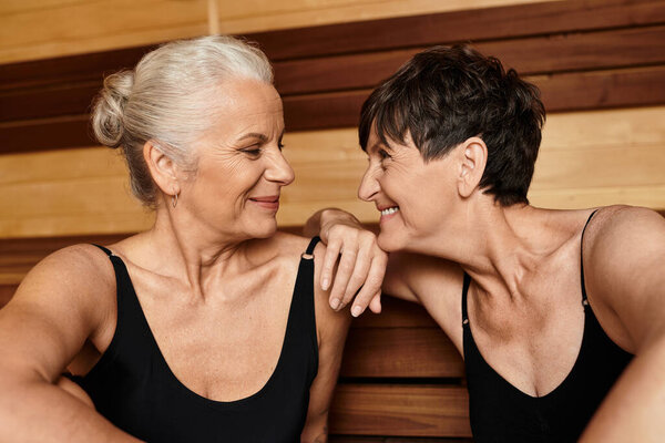 Two beautiful mature women enjoy each others company in a relaxing wellness center atmosphere.