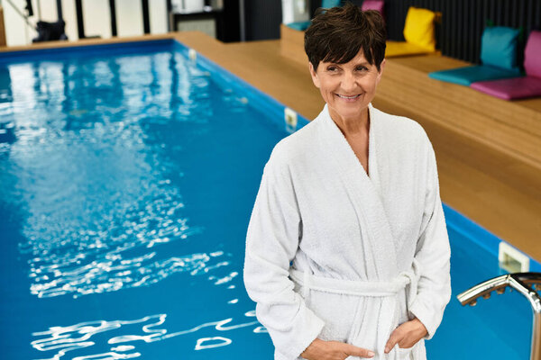 A beautiful mature woman relaxes by the pool in a wellness center designed for active seniors.