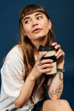 Uzun saçlı güzel genç bir kadın bir içecek tutuyor, incelikle bakıyor..