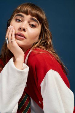 Düşüncesiz genç bir kadın çenesini eline dayar, düşünceli bir şekilde giyinir..