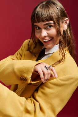 Güzel bayan öğrenci, çarpıcı sarı bir ceketle cesur bir arka plana karşı neşeyle poz veriyor..