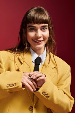 Canlı sarı ceketli neşeli genç bir kadın coşkuyla poz veriyor, oyuncu tarafını gösteriyor..