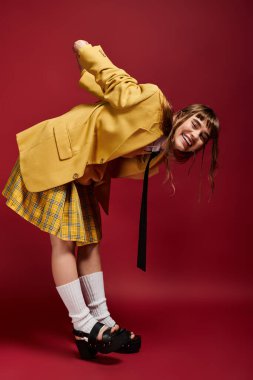 Şık sarı ceketli, kareli etekli, beline eğilmiş genç bir öğrenci..