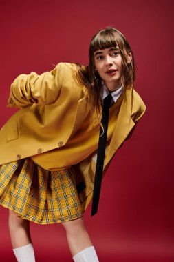 Neşesini ve güvenini ifade eden genç bir kadın, neşeli duruşuyla modaya uygun bir görünüm sergiliyor..