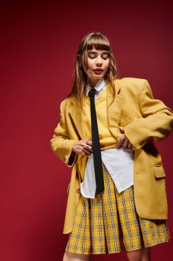 Genç bir kadın kendine güvenerek şık elbisesini bir stüdyoda koyu renkli bir kontrast ile sunar..