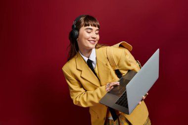 Parlak giyimli kadın dizüstü bilgisayarıyla uğraşırken gülümsüyor, neşeli bir öğrenme anını kucaklıyor..