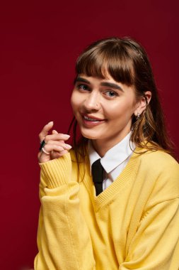 Neşeli bir gülümsemesi olan genç bir kadın çalışkan doğasını sergilerken rahat sarı bir kazak giyer..