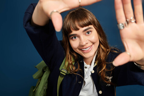 Attractive female student enjoys a moment of joy and enthusiasm with open hands.