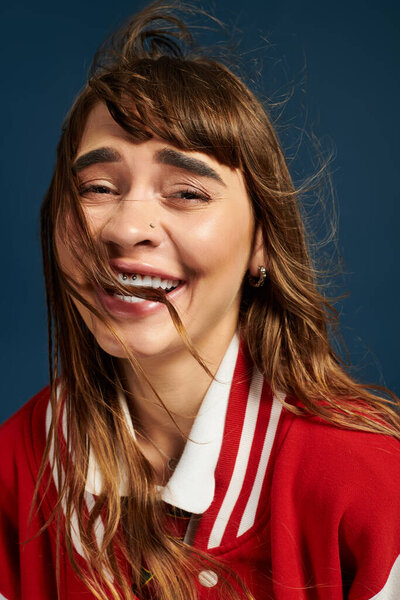Bright smile radiates joy as a young woman in red jacket captures a carefree moment while studying.