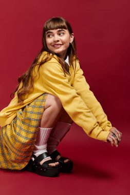 Neşeli genç bir kadın neşe saçan canlı bir kıyafetin içinde çömelir..