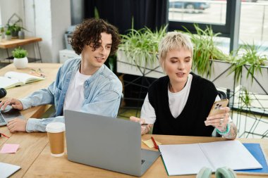 İki motive olmuş genç birey görevlerine odaklanmış, parlak bir ofis masasında birlikte çalışırlar..