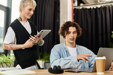 İki genç profesyonel, canlı bir ofis ortamında iş birliği yapıyor, odaklanmış ve meşgul..