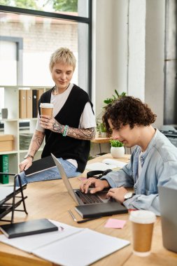 İki genç profesyonel, parlak bir ofisteki görevlerine dalmış, fikir alışverişinde bulunuyor ve odaklanıyorlar..