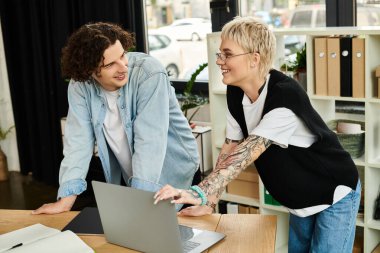 Modern bir ofis masasında birlikte çalışan iki genç profesyonel, fikir ve stratejilerini paylaşıyor..