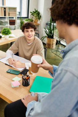 İki genç profesyonel, hayat dolu bir ofiste, kahve ve notlar üzerine fikir alışverişinde bulunuyorlar..