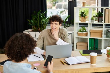 Parlak bir ofiste işbirliği yapan iki genç profesyonele odaklanın, fikir ve strateji alışverişinde bulunun.