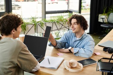 İki genç insan, parlak bir ofis çalışma alanında fikir ve ilham paylaşımı yaparak iş birliği yapıyor..
