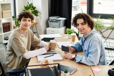 İki genç profesyonel, not defterleri ve kahve fincanlarıyla dolu bir masadaki görevlere odaklanıyor..