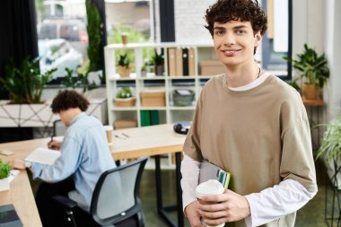 Motive olmuş bir genç, başka bir meslektaşı dikkatle masa başına odaklanırken iş görevlerine girişir..