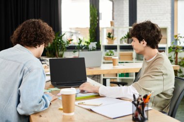 Yeşillik dolu çağdaş bir ofis çalışma alanında iki çalışkan genç takım çalışması yapıyor..
