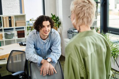 İki genç profesyonel yeşillik ve ışıkla dolu canlı bir ofiste etkileşim halindeler..