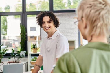 Genç bireyler parlak bir ofis ortamında iş birliği yapıyorlar, fikir alışverişinde bulunuyorlar ve gülümsüyorlar..