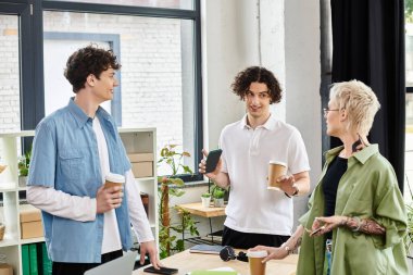 Enerjik gençler, yeşillik dolu modern bir ofiste kahve eşliğinde iş birliği yapıyorlar..
