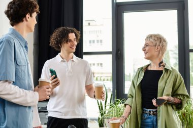 Üç genç profesyonel iş birliği yaparken aynı anda hem kahve hem de fikir alışverişinde bulunuyor..