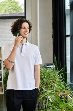 Yeşillik ve doğal ışıkla dolu modern bir ofiste genç bir işçi telefonda konuşuyor..
