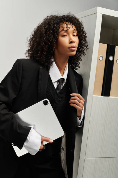 A stylish young woman stands beside a filing cabinet, showcasing her grace and professionalism.