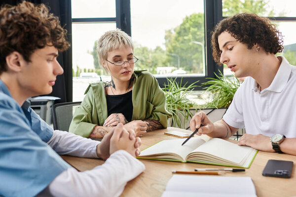 Три молодых специалиста, участвующих в дискуссии во время работы над проектом за столом.