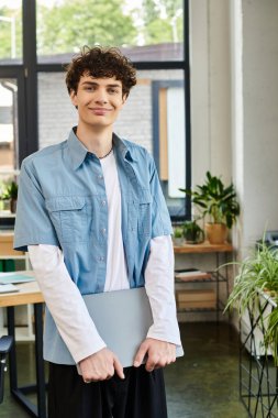 Genç adam kendine güvenen parlak bir ofiste duruyor, görevleri ve projeleri yerine getirmeye hazır..