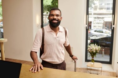Afro-Amerikalı şık bir adam otelin lobisine güvenle gülümsüyor, seyahatlerine hazır..