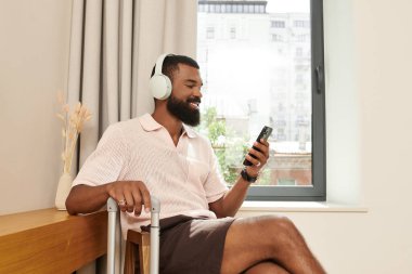 Afro-Amerikalı şık bir adam tatilde bir otel odasında dinlenirken müzik dinlemekten hoşlanır..