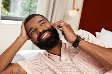 Yakışıklı bir adam, şık bir otel odasında telefonla eğlenirken dinleniyor..