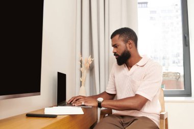 Şık bir otel odasında bakımlı bir adam tatildeyken dizüstü bilgisayarına odaklanır..