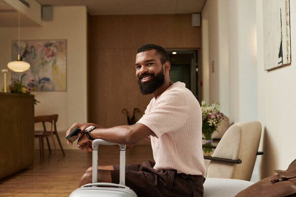 Уверенный в себе, стильный мужчина сидит со своей возлюбленной в шикарном холле отеля, наслаждаясь отпуском.