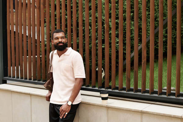 Стильный афроамериканец расслабляется в современной городской обстановке, наслаждаясь кофе.