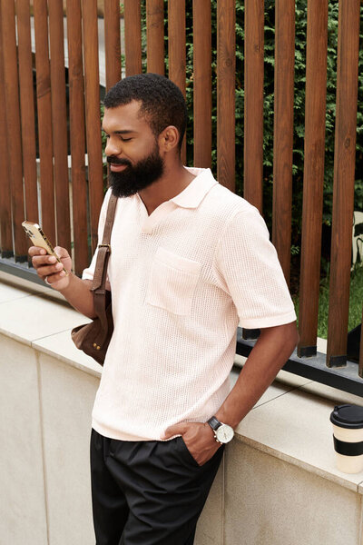 В оживленном городе хорошо одетый афроамериканец проверяет свой телефон, расслабляясь..