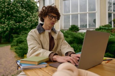 Genç adam yemyeşil ve sıcak güneş ışığıyla çevrili, özenle dışarıda çalışıyor..