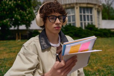 Genç bir adam dışarıda huzurlu bir gezinti yapar, notlarını gözden geçirir ve çalışmalarını gözden geçirir..