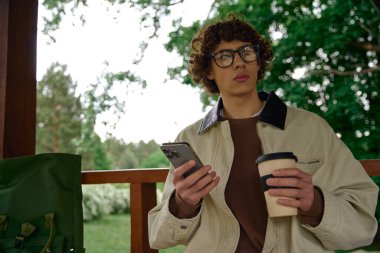 Öğrenci, kahve ve telefonuyla doğanın kıymetini bilerek dışarı çıkar..