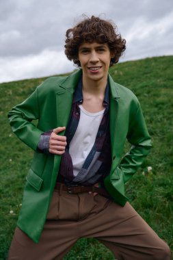 Neşeli genç bir adam yemyeşil çimlerde dolaşır, temiz havayı kucaklar ve güzelliği kucaklar..