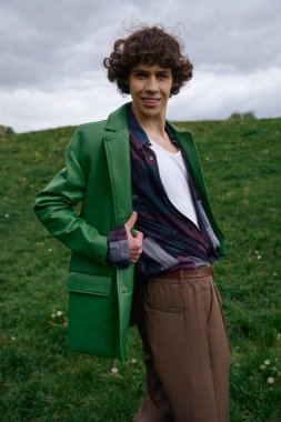 Yakışıklı öğrenci çimenli arazide neşeyle yürüyor, temiz havayı ve doğayı kucaklıyor..