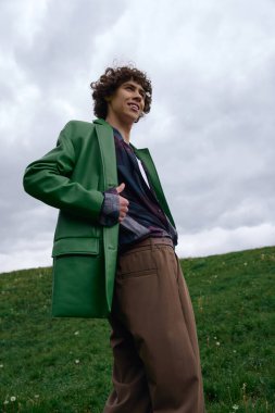 Kendine güvenen genç bir adam, gösterişli tarzını sergileyerek otlak bir tepede sakin bir yürüyüş yapar..